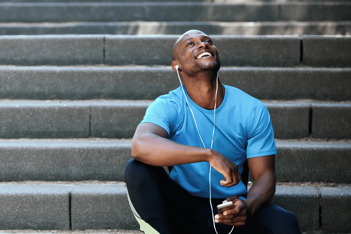 manifest happiness man smiling on stairs with headphones