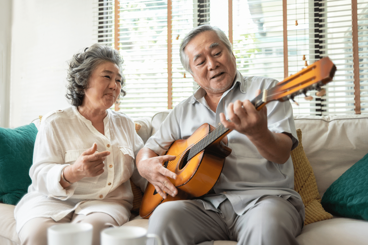 older couple on sofa playing guitar and singing